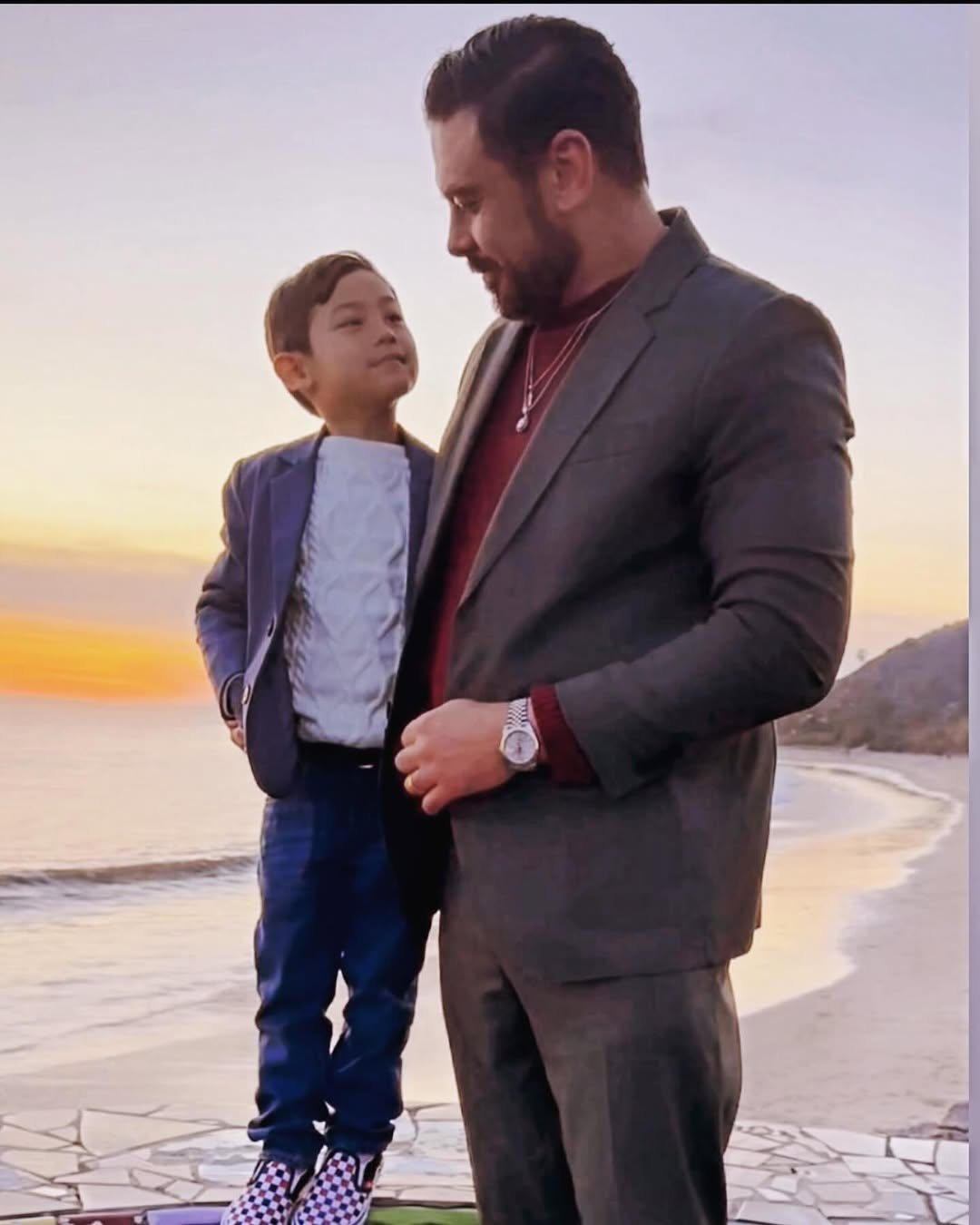 Roland in a suit with Koji at sunset on the beach